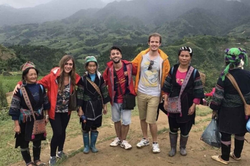 A group of people standing on a dirt path with a mountainous landscape in the background. 3