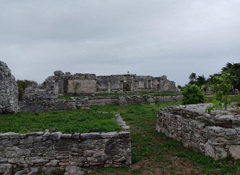 Ancient stone ruins with overgrown grass and a cloudy sky. 1
