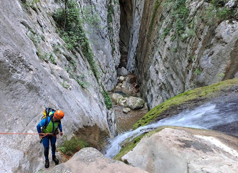 A person rappelling down a rocky cliff with a flowing river below. 5