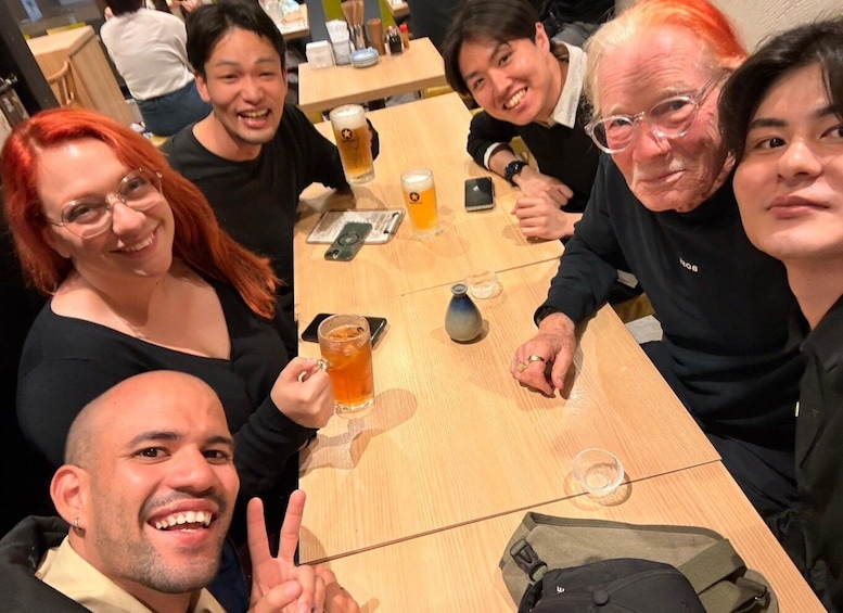 A group of people sitting around a wooden table with drinks and a smartphone. 3