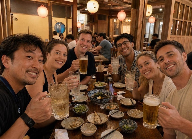 A group of people sitting at a wooden table in a restaurant with various dishes and glasses of beer. 5