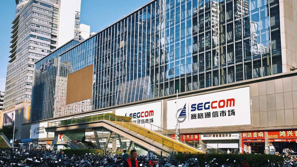 A modern building with large glass windows and multiple advertisements, including a prominent SEGCOM sign. 3