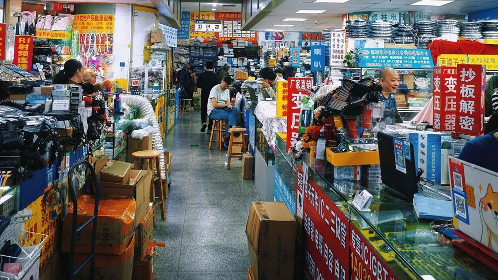 A busy electronics store with various products on display and customers browsing. 2