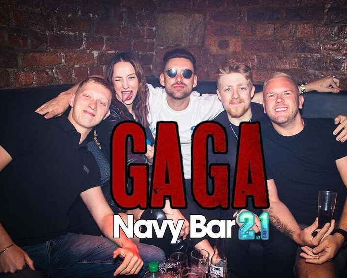 A group of people at a bar with a brick wall background and the text 'GAGA Navy Bar 21'. 5