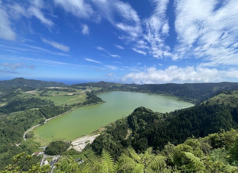A lake surrounded by forested hills under a partly cloudy sky. 1