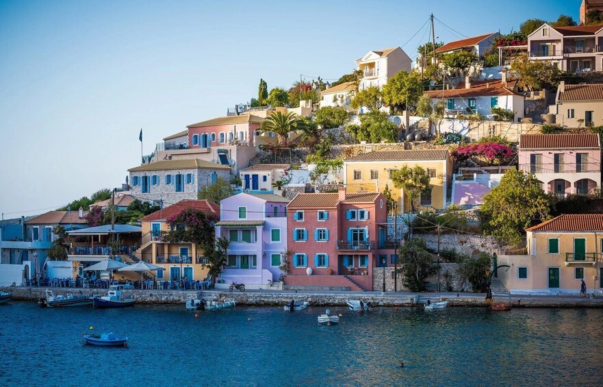 A coastal town with colorful buildings, a clear blue sea, and boats docked along the waterfront. 1