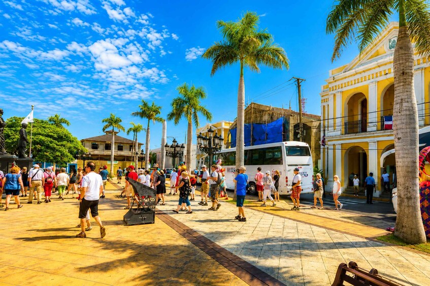 A busy street scene with pedestrians, palm trees, and a bus. 2