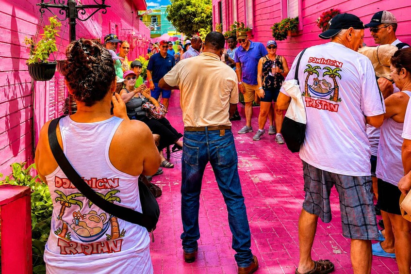 A group of people walking down a pink-painted street. 5