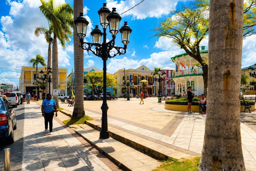 A sunny plaza with palm trees, street lamps, and historic buildings. 4