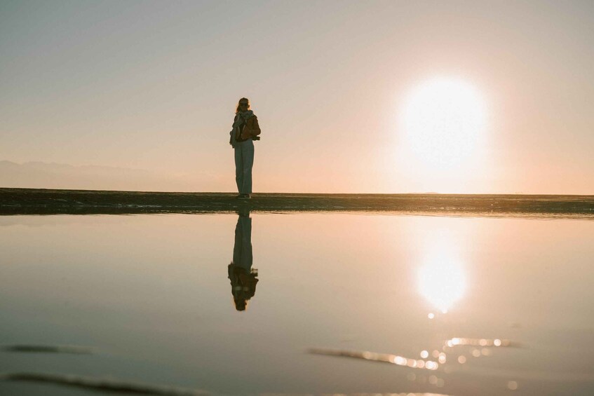 A person standing on a reflective surface with a sunset in the background. 3