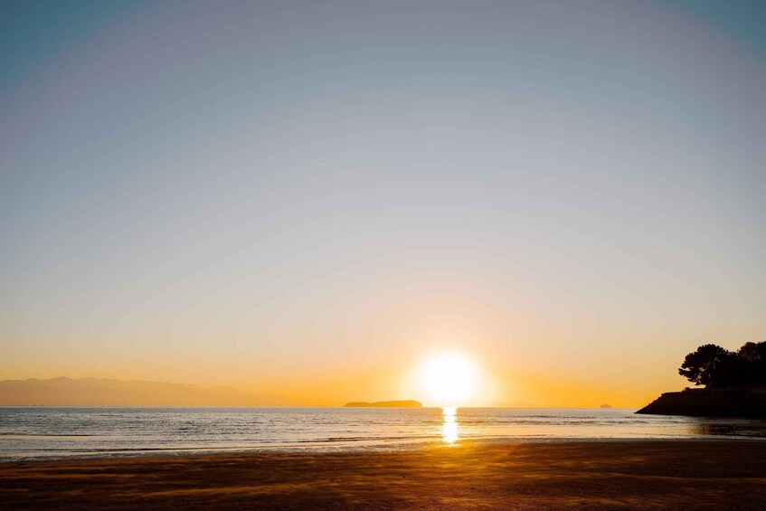 A sunset over a beach with the sun low on the horizon, casting a warm glow. 5