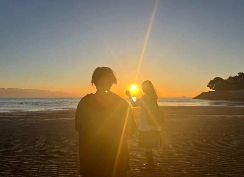 A beach at sunset with silhouettes of people and a clear sky. 4