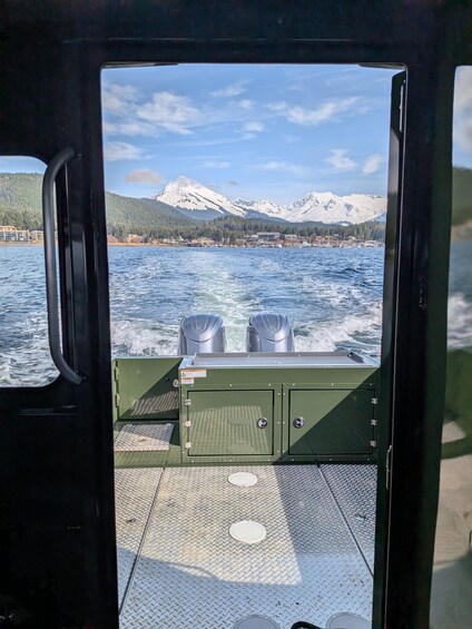 A boat's interior with a view of a lake, mountains, and a dock. 3