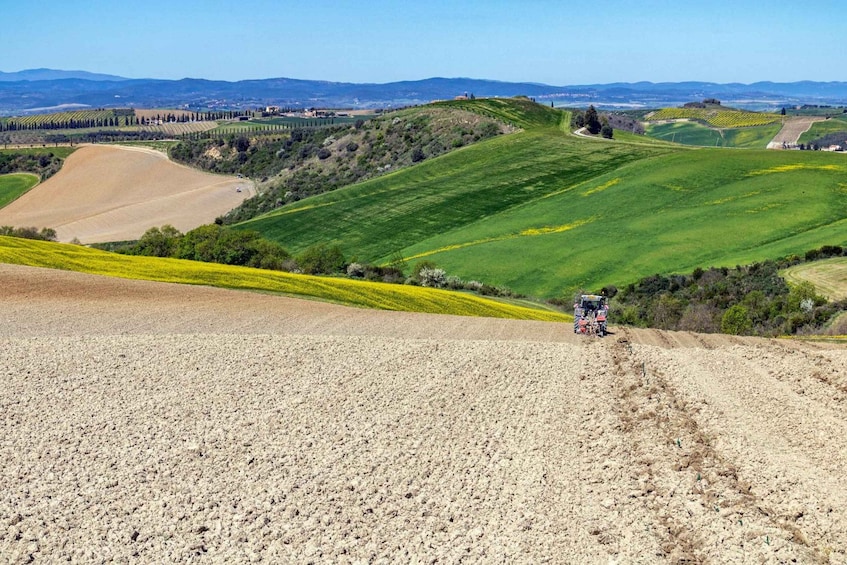 A tractor on a plowed field with rolling hills and distant mountains. 5