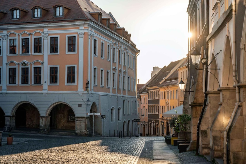 A cobblestone street lined with historic buildings, featuring arched doorways and traditional architecture. 4