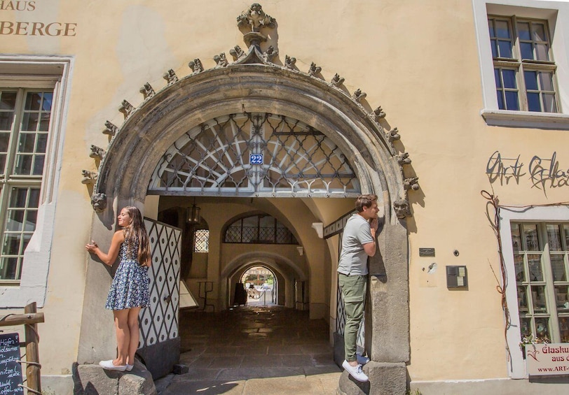 A historic building entrance with an ornate archway, a sign with the number 22, and a person standing on the steps. 3