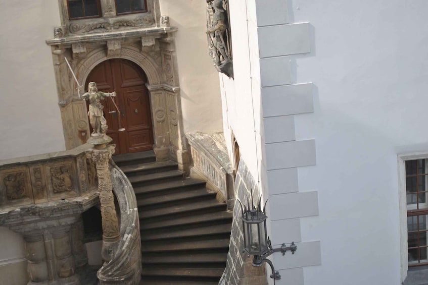 A building with a wooden door, stone steps, and a statue. 2