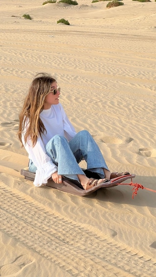 A person sitting on a sled in a sandy desert landscape. 2