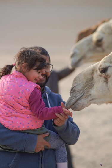 A person holding a child near a camel. 3