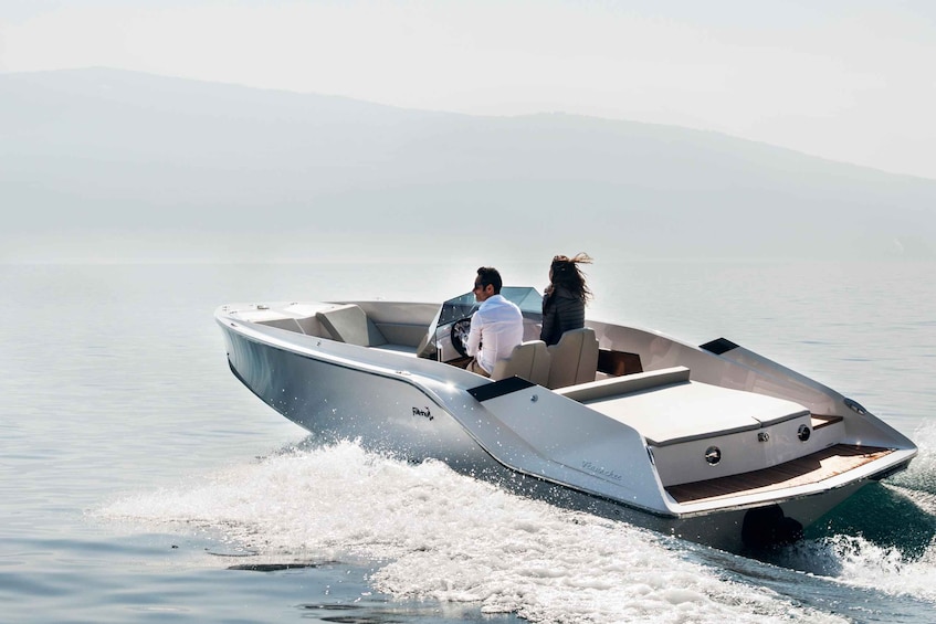 Un bateau à moteur avec deux passagers navigue sur un lac calme, entouré d’un paysage montagneux brumeux. 3