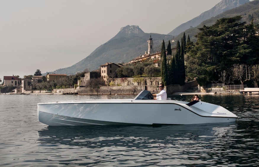 Un élégant bateau blanc sur une eau calme, avec en arrière-plan des montagnes et des bâtiments historiques. 4