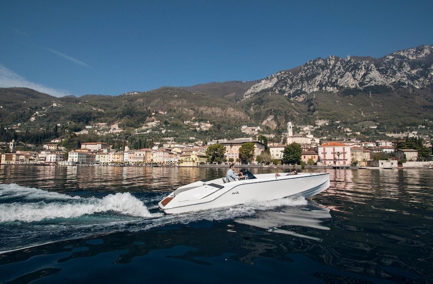 Un bateau à moteur sur un lac, avec une ville et des montagnes en arrière-plan. 1