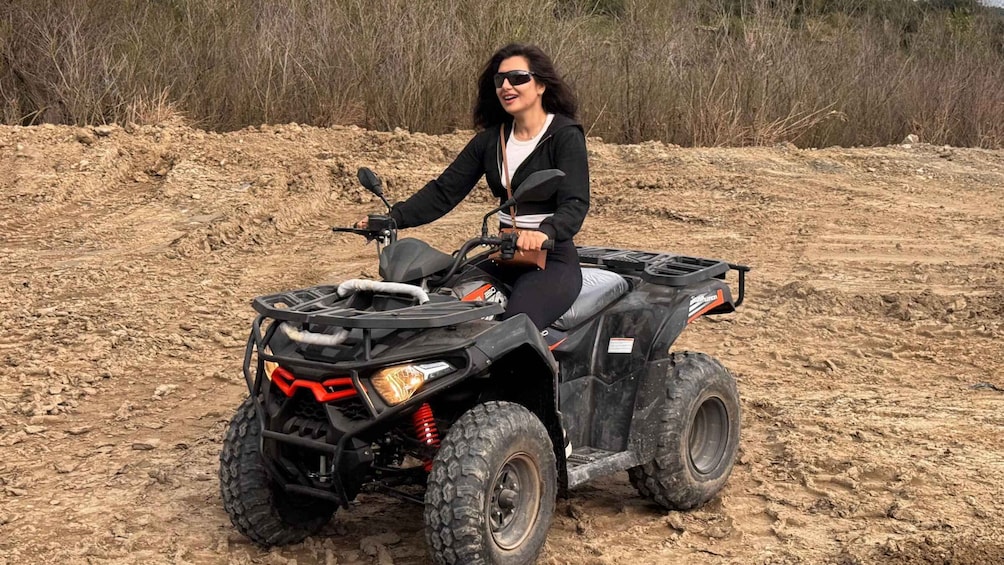 A person on a quad bike in a dirt area with sparse vegetation. 4