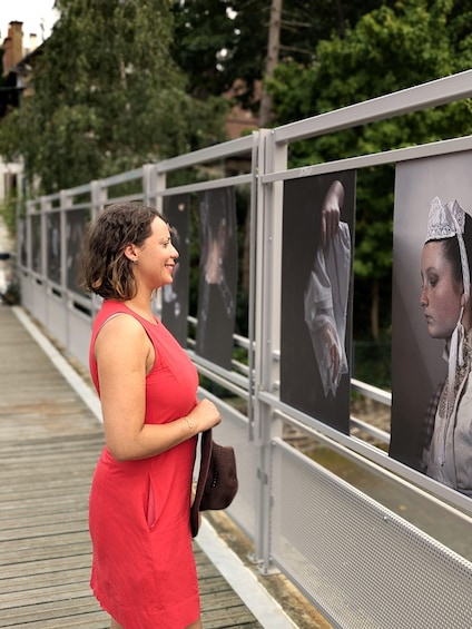 A person standing on a bridge, looking at a series of posters on the railing. 1