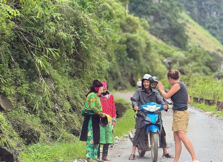A group of people on a rural road with lush greenery on both sides. 2