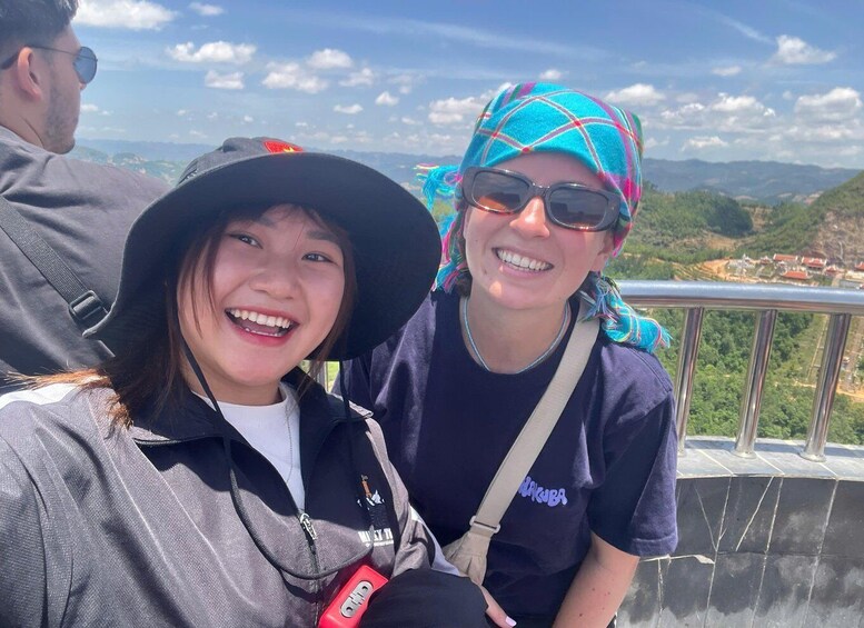 Two people sitting on a ledge with a mountainous landscape in the background. 3