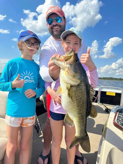 A person holding a fish, a boat, and a clear sky. 1