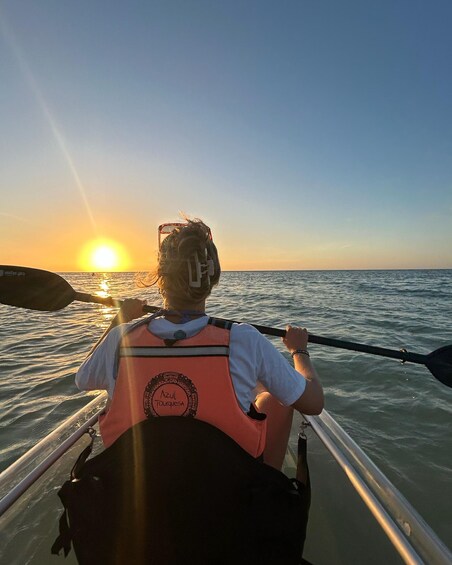 A person in a kayak with a life jacket, paddling on calm waters during sunset. 2