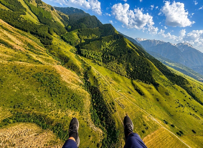 A person standing on a grassy hillside with a mountain range in the background. 5