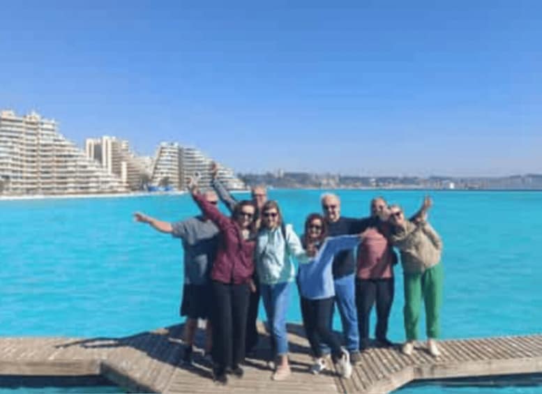 A group of people posing on a pier with a city skyline and water in the background. 3