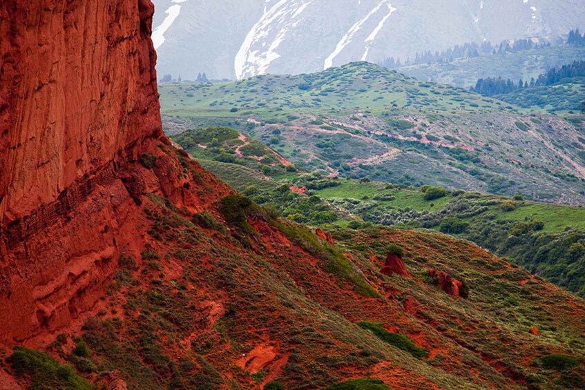 A red rock cliff, green hills, and a valley. 2