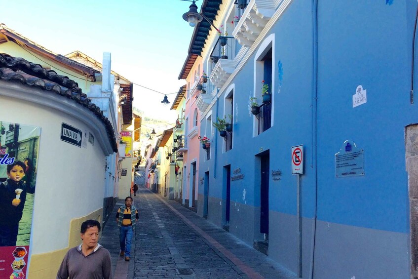 A narrow street lined with colorful buildings, a 'NO ENTRY' sign, and a person walking down the street. 2
