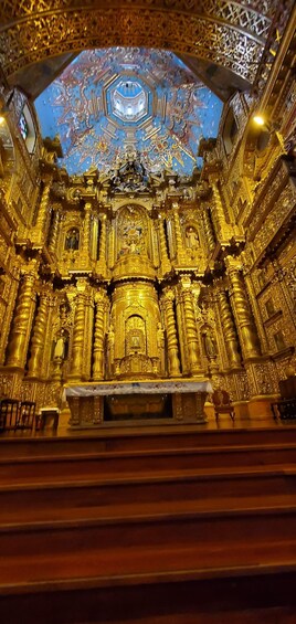 An ornate interior with golden decorations, a central altar, and a detailed ceiling. 5