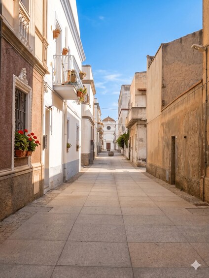 A narrow street flanked by buildings with balconies, a clear sky, and a distant church. 3