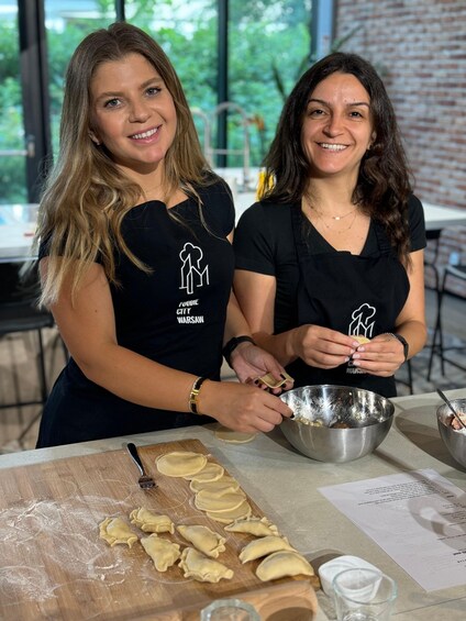 Two people preparing food, with dough on a cutting board and ingredients in bowls. 2