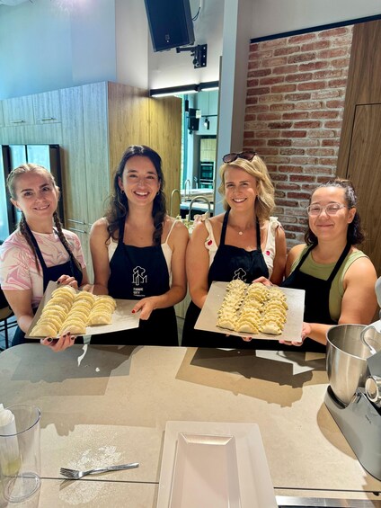 Four people holding trays of food in a kitchen. 3