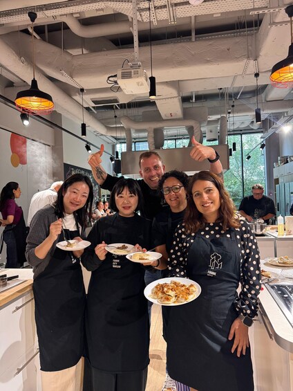 A group of people in a modern kitchen with industrial elements, holding plates of food. 4