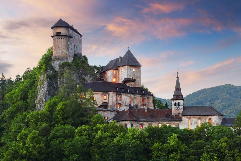 A historic castle with a tower, surrounded by lush greenery and a church with a steeple. 4