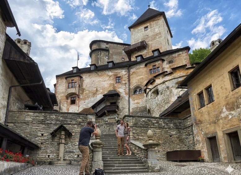 A historic stone building with a tower, a staircase leading up to it, and a photographer capturing the scene. 4