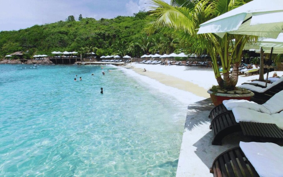 A beach with clear turquoise water, lounge chairs, and umbrellas. 2