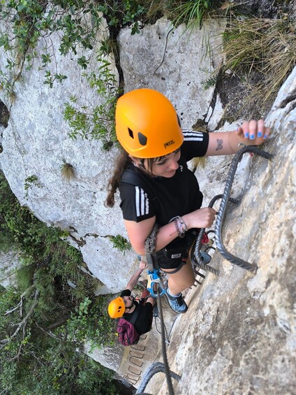 A person rappelling down a rocky cliff with a helmet and harness. 5