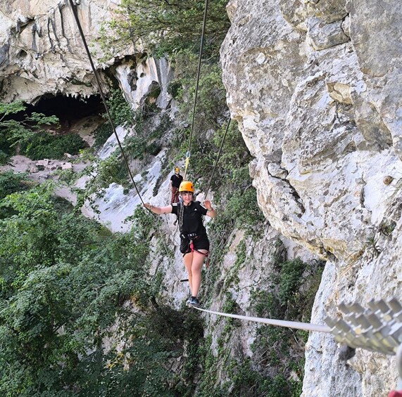 A person zip-lining through a rocky gorge with vegetation. 4