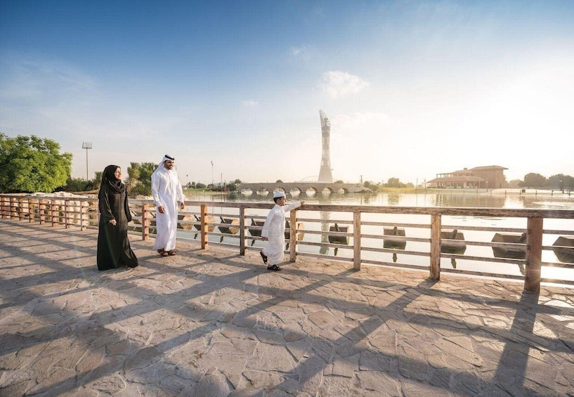 A stone bridge with a railing, a body of water, and a tall tower in the background. 3