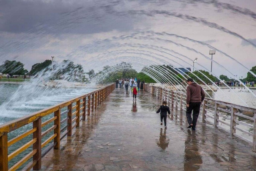 A wet pedestrian bridge over water with people walking. 2