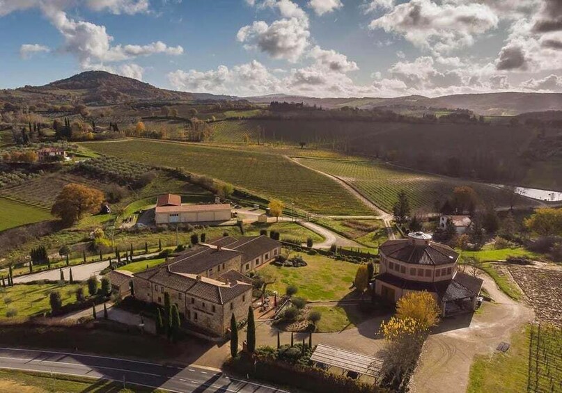 A rural landscape with rolling hills, a vineyard, and a historic building complex. 2