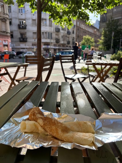 A picnic table with a wrapped food item and a tree in the background. 5
